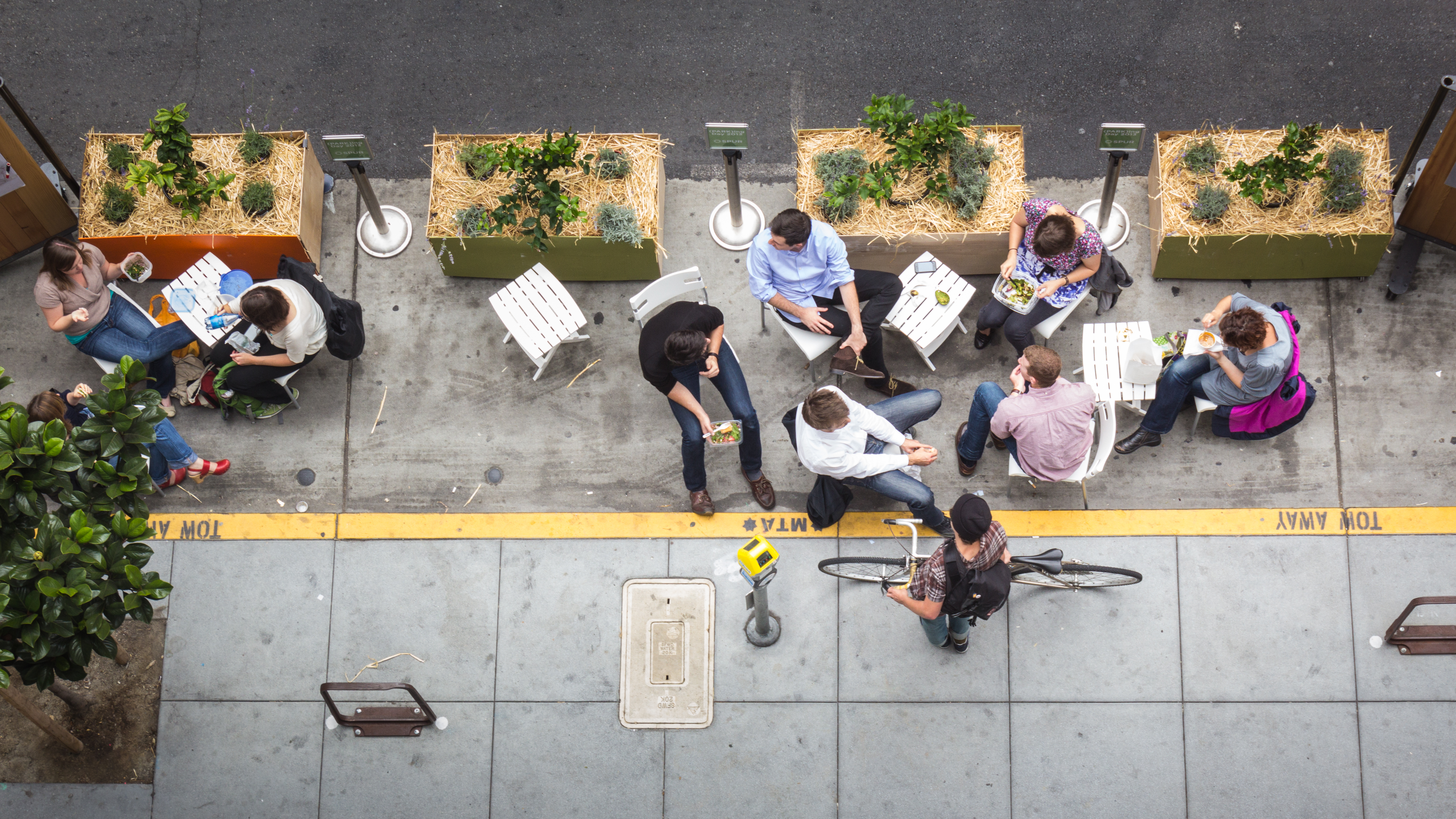 A picture of people sitting down at a streetside spot